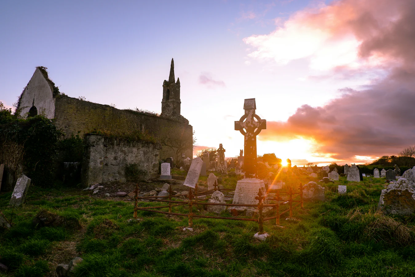 Church ruins and a stone cross at sunset; an illustrative scene for Irish family history.